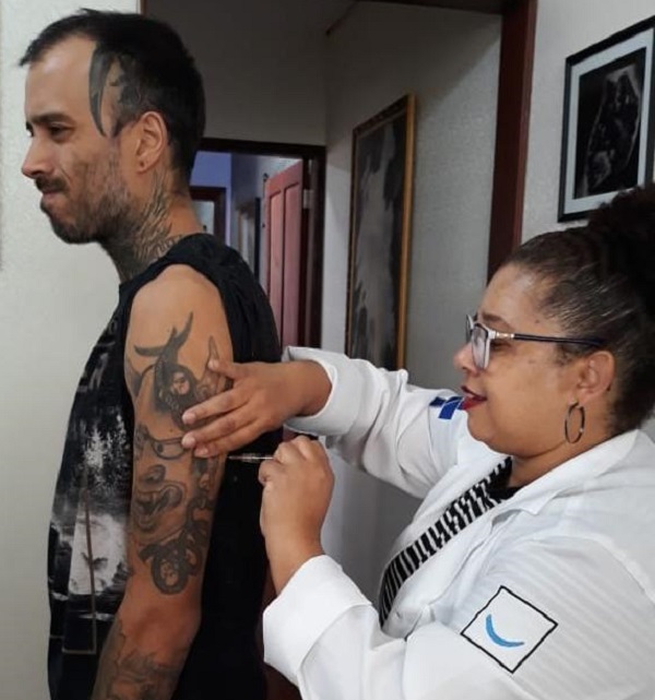 #PraCegoVer: Na foto, agente de saúde aplica a vacina contra o Sarampo em um estudante durante ação realizada em uma universidade